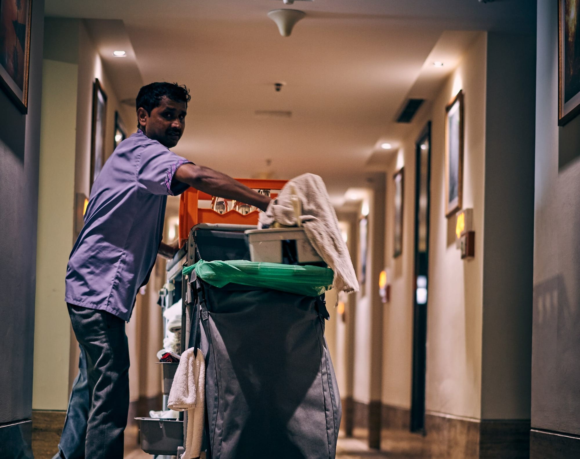 man in blue dress shirt and blue denim jeans holding green plastic bag