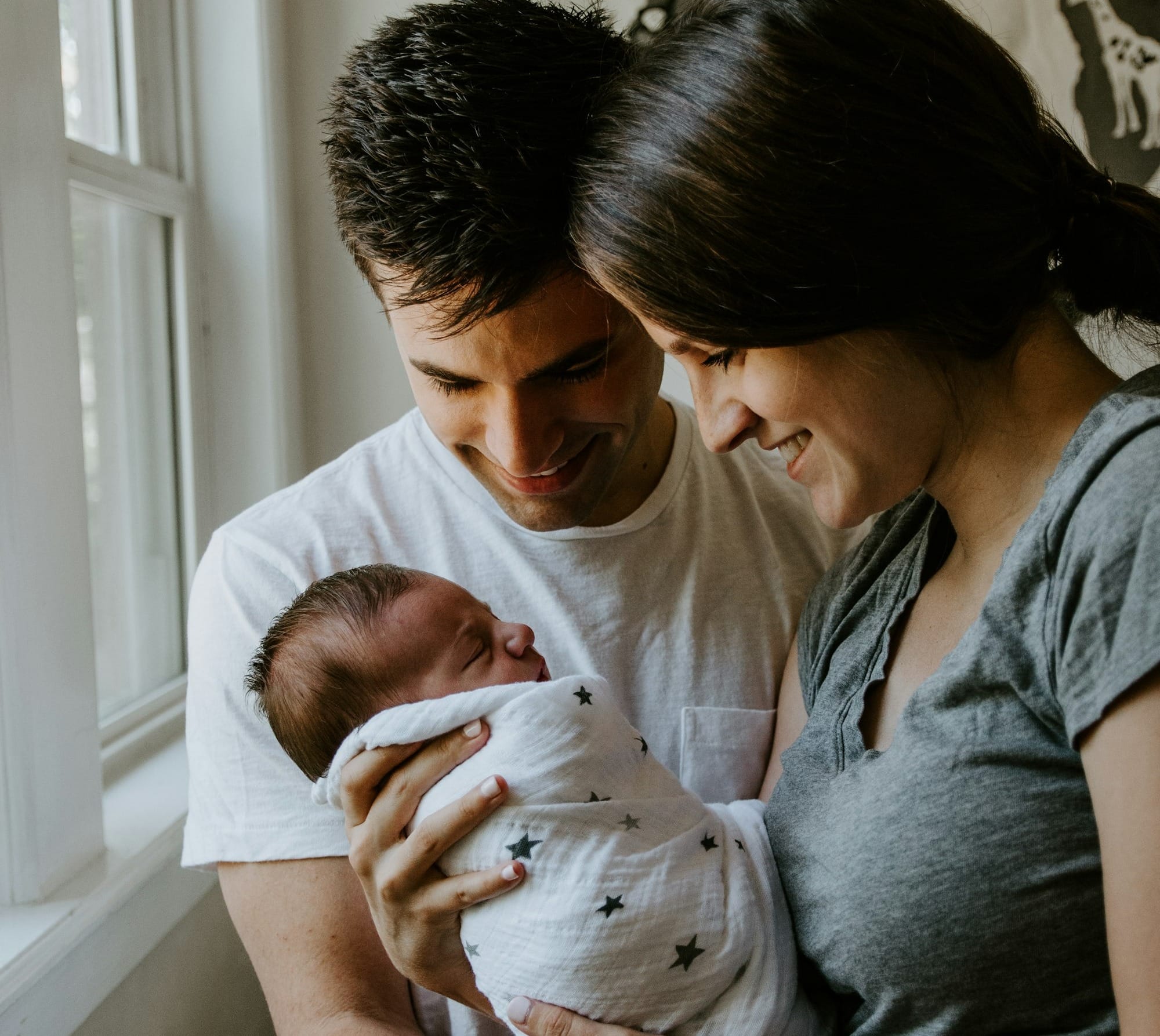 woman holding baby beside man smiling