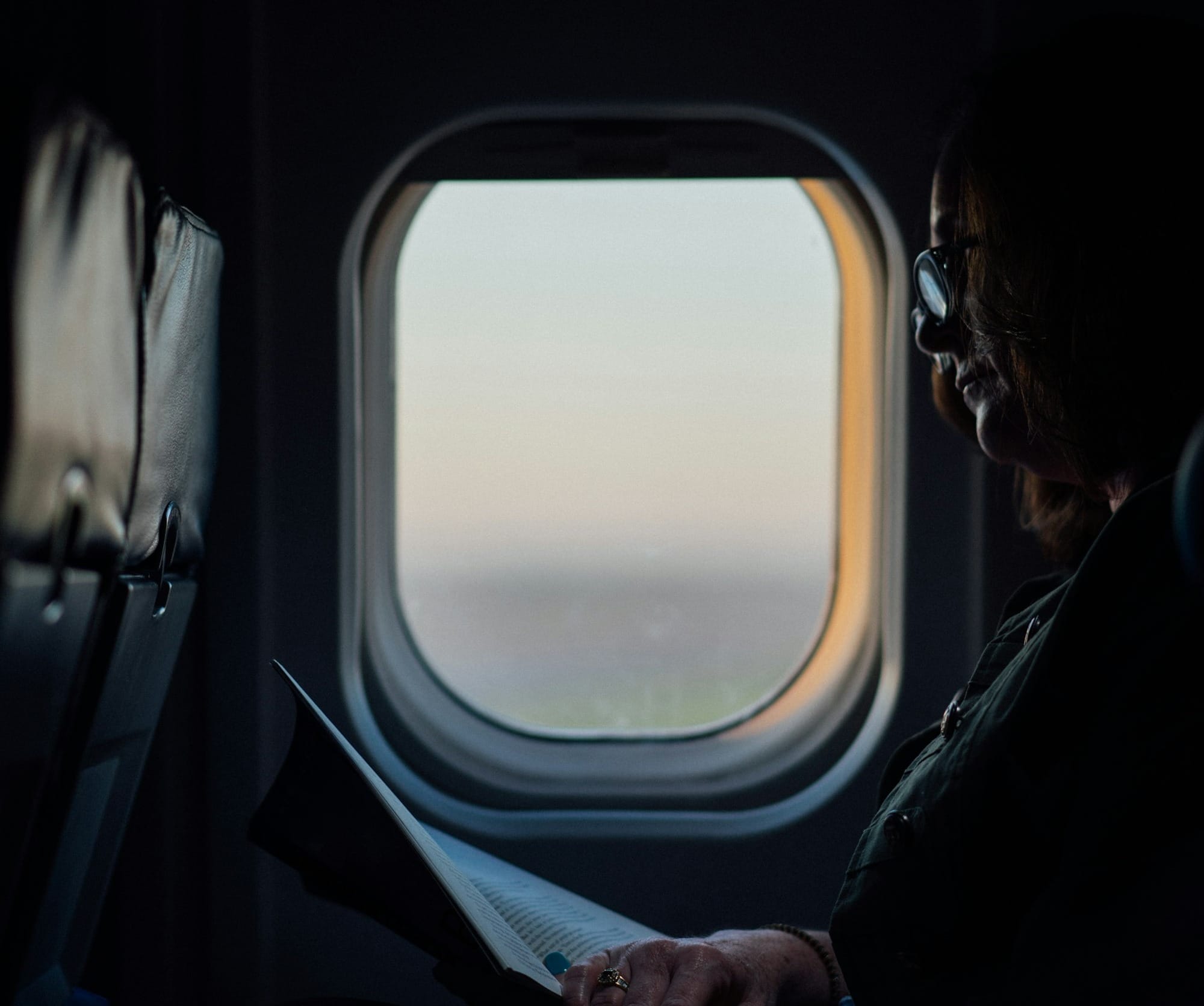 woman sitting and reading book on airliner